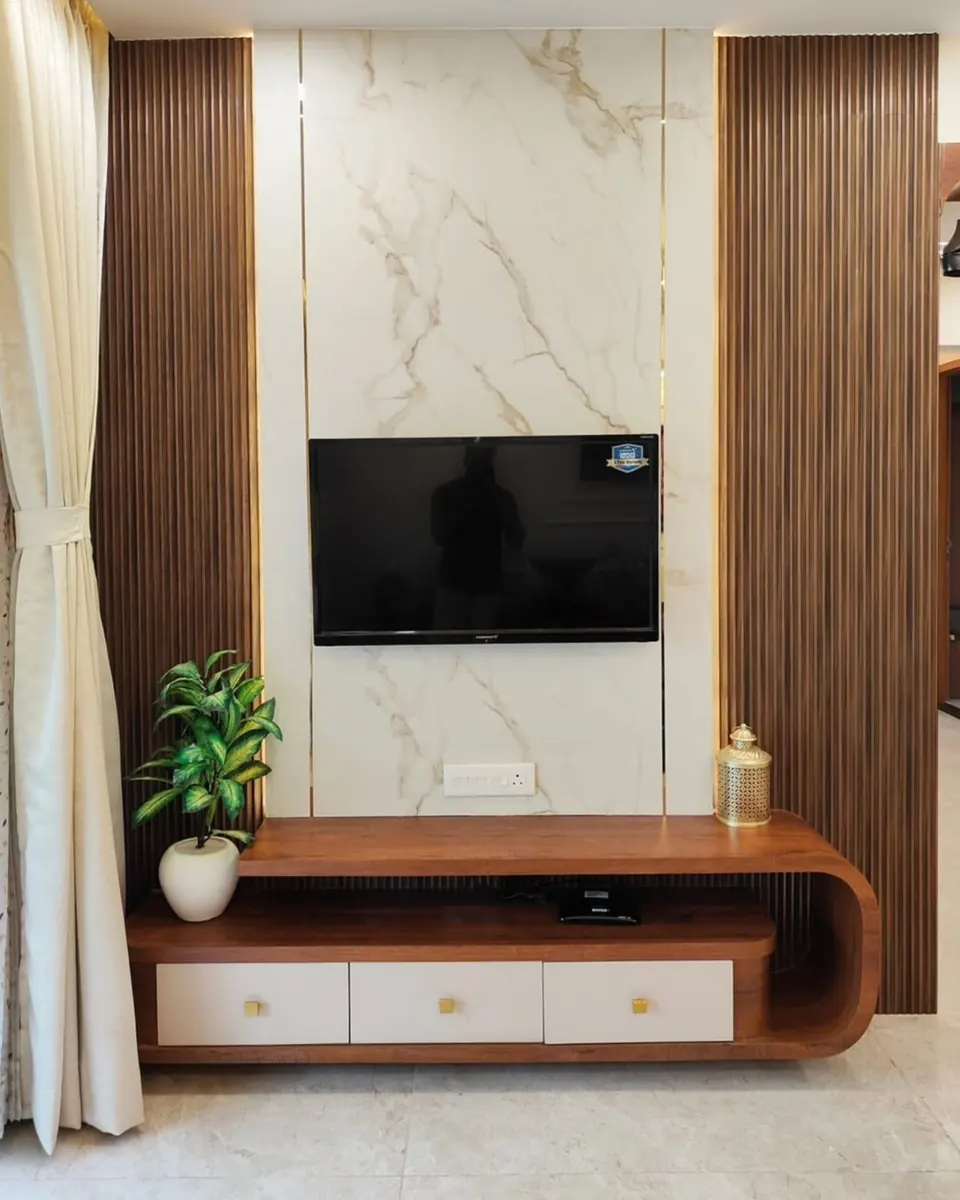 TV wall with a marble-look panel between fluted wood panels and a curved wood console